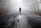 Lonly woman  walk away into the misty foggy road in a dramatic mystic scene. Girl walking in a foggy autumn landscape