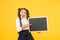 Look at this. Happy girl pointing finger at blackboard on yellow background. Small kid with blank blackboard. Little