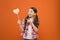 Look at this heart. Cute little child pointing finger at prop heart on orange background. Adorable small girl holding