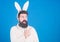 Look at that. Hipster dressed for Easter party presenting product. Bearded man in Easter rabbit costume. Man wearing