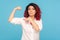 Look, I`m strong! Portrait of proud woman with fancy red hair pointing to biceps on raised hand