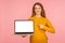 Look at Internet advertising. Portrait of cheerful ginger girl in sweater holding laptop and pointing at empty screen, copy space