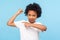 Look at my muscle, I`m strong. Portrait of adorable little boy in T-shirt pointing at biceps, feeling powerful and self-confident