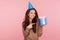 Look at my present! Portrait of joyful young woman wearing party cone on head and pointing at gift box