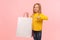 Look at my purchase! Portrait of charming happy little girl pointing at shopping bags and smiling at camera
