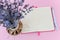 Look at opened paper notepad in a pink cover through fragrant bouquet of dry lavender with small purple flowers