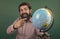 look over there. back to school. informal education. happy mature teacher pointing at globe. bearded man geographer work