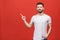 Look over there! Happy young handsome man in casual pointing away and smiling while standing against red background