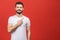 Look over there! Happy young handsome man in casual pointing away and smiling while standing against red background