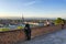 Look at the panorama of the city from hill viewpoint on the brick wall of the terrace at sunset