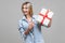 Look at this present! Portrait of excited woman pointing at wrapped gift box. satisfied with holiday surprise. indoor studio shot