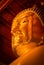 Look up view and close-up face of golden buddha statue in buddhist hall, Thailand.