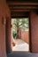 Looking through an adobe walkway to a wall and pine tree outside in Santa Fe New Mexico