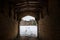 Looking through ancient gatehouse to view of abandoned old derelict run down eerie Manor House boarded up dark creepy winter snow