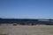 Looking from a beach with driftwood across the water to a pier