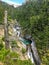 Looking through the branches of an evergreen forest to a beautiful steep waterfall high in the Rocky Mountains