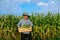 Looking at camera senior male worker carries box of ripe corn, the man shows his crop, front view