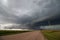 Looking down a dirt road at a supercell thunderstorm.