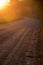 Looking down a road that bends to the left with golden sunlit hazy skies