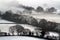 Looking down on snow covered English farmland. With trees silhouetted on a cold, winters, misty day