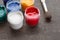 Looking down on three open paint cans of coloured paint stood on a shabby style wood floor