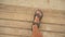 Looking down to young man feet in brown leather sandals walking over wooden boards path on sandy beach