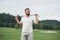 Looking far away. Portrait of standing golf player in the lawn and stick in hand. Woods at background