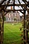 Looking through a garden archway at a mansion house