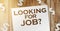 Looking for job .words asking someone to work together for certain job or project. Page on wooden backdrop and paper dollar signs