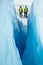 Looking through a narrow crevasse at two women ice climbers walking away on the Matanuska Glacier in Alaska