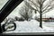 Looking out car window at piled up snow drifts and a convenience store in the distance with rear view window showing more snow