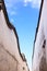 Looking skyward in a hutong alley between two white traditional brick concrete walls and tiles