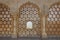 Looking through stone lattice window to the walls of Amber Fort; Amer, Jaipur, India