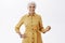 Looking stylish as always. Portrait of energized and charismatic elderly woman in fashionable yellow coat playing with