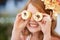 Looking sweet. A little girl playfully holding cupcakes in front of her eyes.