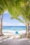 Looking through tropical palm trees on a white sand beach with a