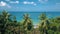 Looking through tropical tree leaves at the beautiful lagoon sea water and summer cloudy sky