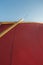 Looking up the rigging of a sailing dinghy: red sail, wooden mast