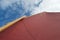 Looking up the rigging of a sailing dinghy: red sail, wooden mast