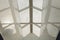 Looking up to the blue cloudy sky through modern square ceiling window.