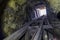 Looking up towards the opening of a mine shaft from inside, interior lit by beam of a flashlight