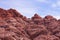 Looking upward at a cliff of jagged, craggy rocks with a blue, cloudy sky in the background. Red Rock, Nevada.