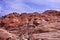 Looking upward at a cliff of jagged, craggy rocks with a blue, cloudy sky in the background. Red Rock, Nevada.