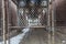 Looking through urban fencing to overhead elevated subway tracks cutting through alleyway