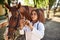 Looks at syringe. Female vet examining horse outdoors at the farm at daytime