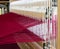 A loom set up with red wool warp threads ready for weaving