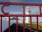 Loop head lighthouse framed by old red metal gates. Warm sunny day, cloudy sky. County Clare, Ireland. Irish history and heritage