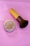 Loose Powder and Powder Brush on a Pink Surface