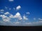 LOOSE WHITE CLOUDS OVER TARMAC OF AIRSTRIP