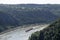 Loreley, Germany - 25 July 2021. A large barge carrying a lot of containers on the Rhine River in western Germany, visible hills o